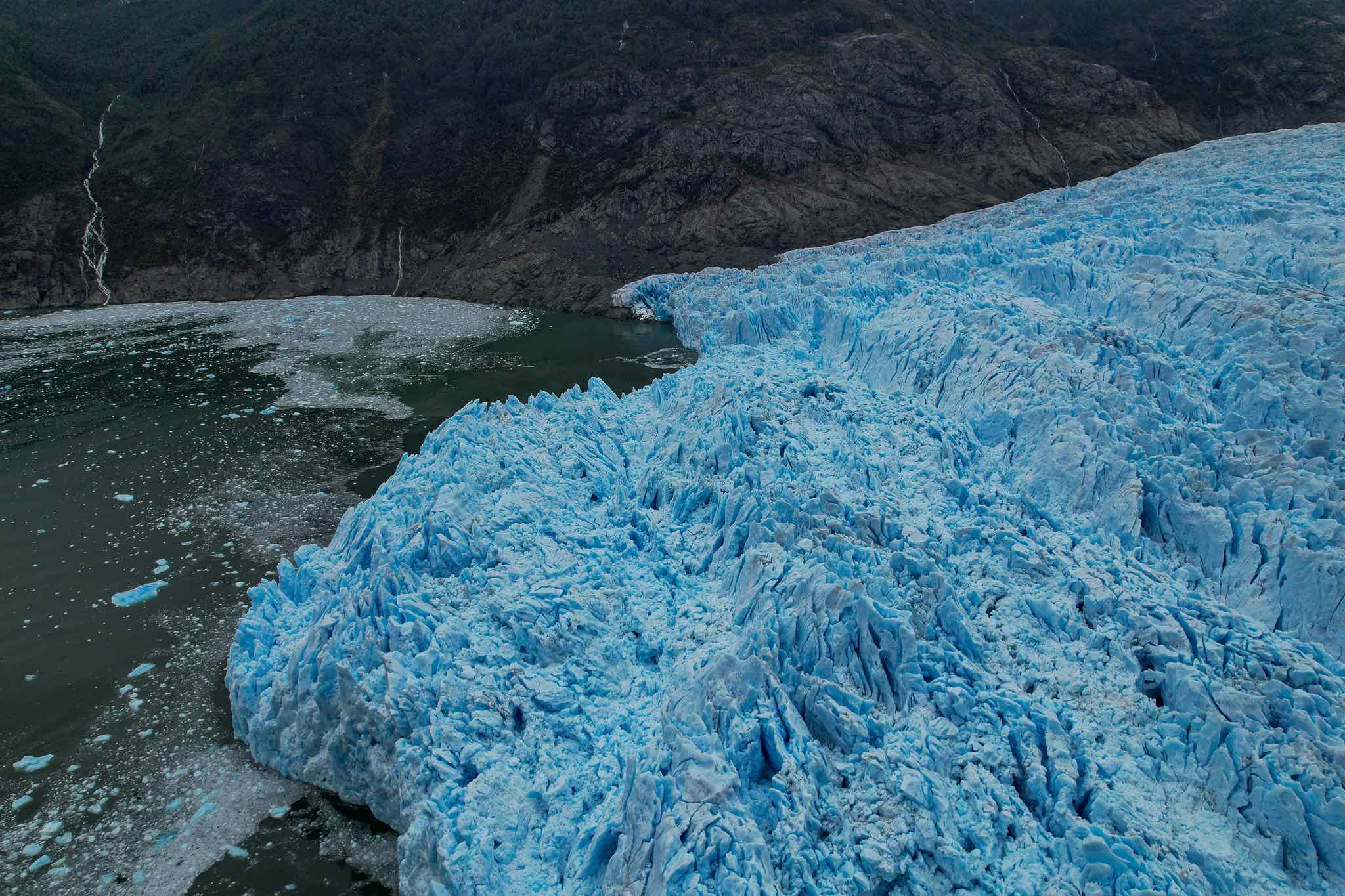 black hiking backpack near white Fujifilm instax mini camera near black leather boots, red half-zip jacket, gray pocket watch on white map