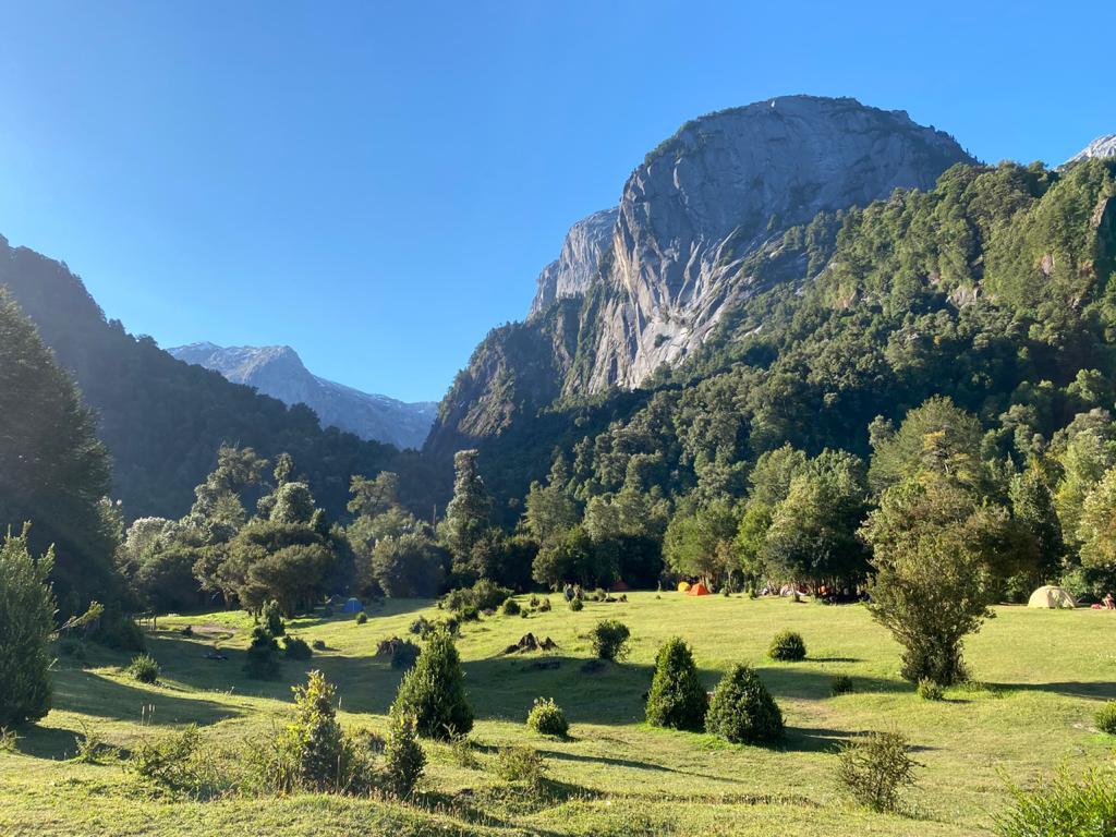 black hiking backpack near white Fujifilm instax mini camera near black leather boots, red half-zip jacket, gray pocket watch on white map